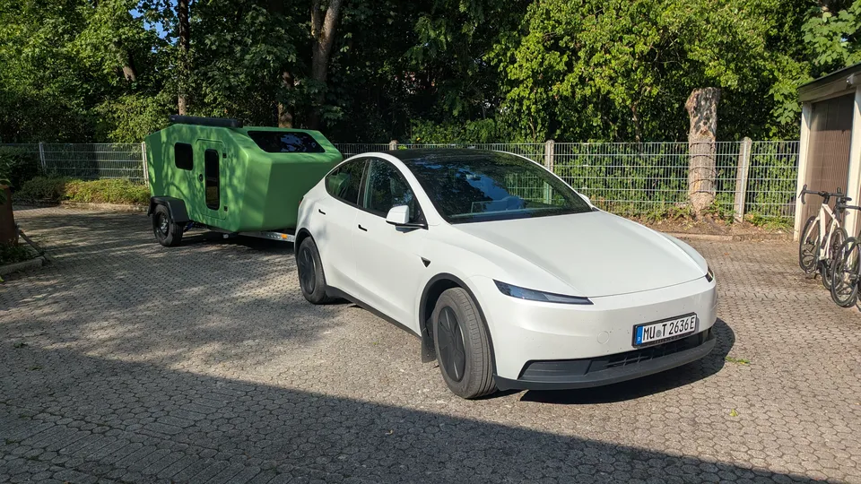 White Tesla Model Y with the green Glide prototype in a paved yard
