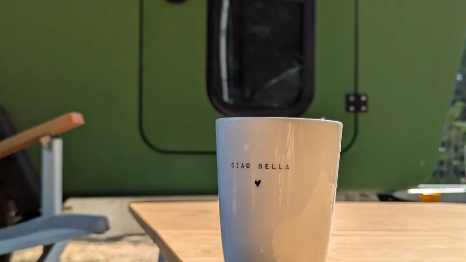 Coffee mug reading Ciao Bella in front of the green Glide