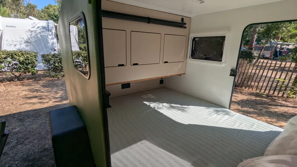 View through the open side door onto the bed and built-in cabinet