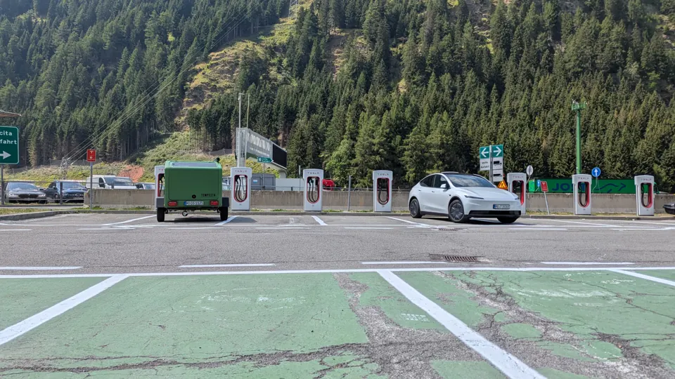 Glide and Tesla Model Y at a Supercharger in front of wooded mountains