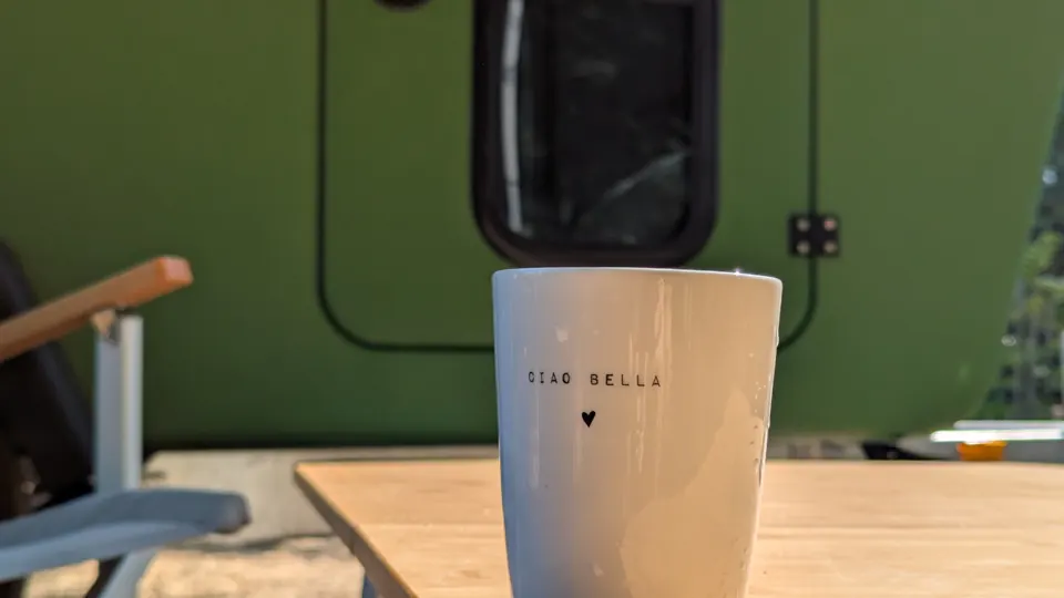 Coffee mug reading Ciao Bella on the bamboo table, the Glide door behind it